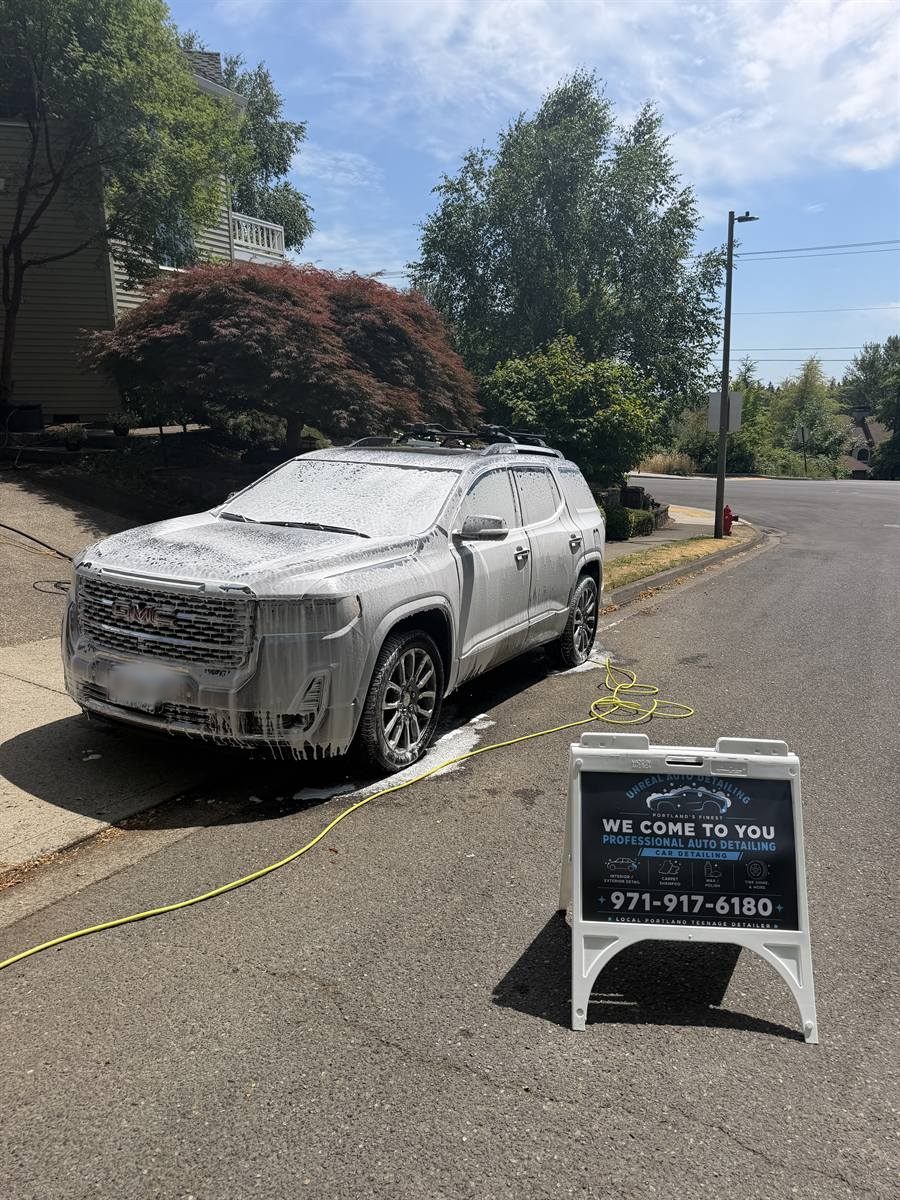 GMC in foam beside the Unreal Auto Detailing sign