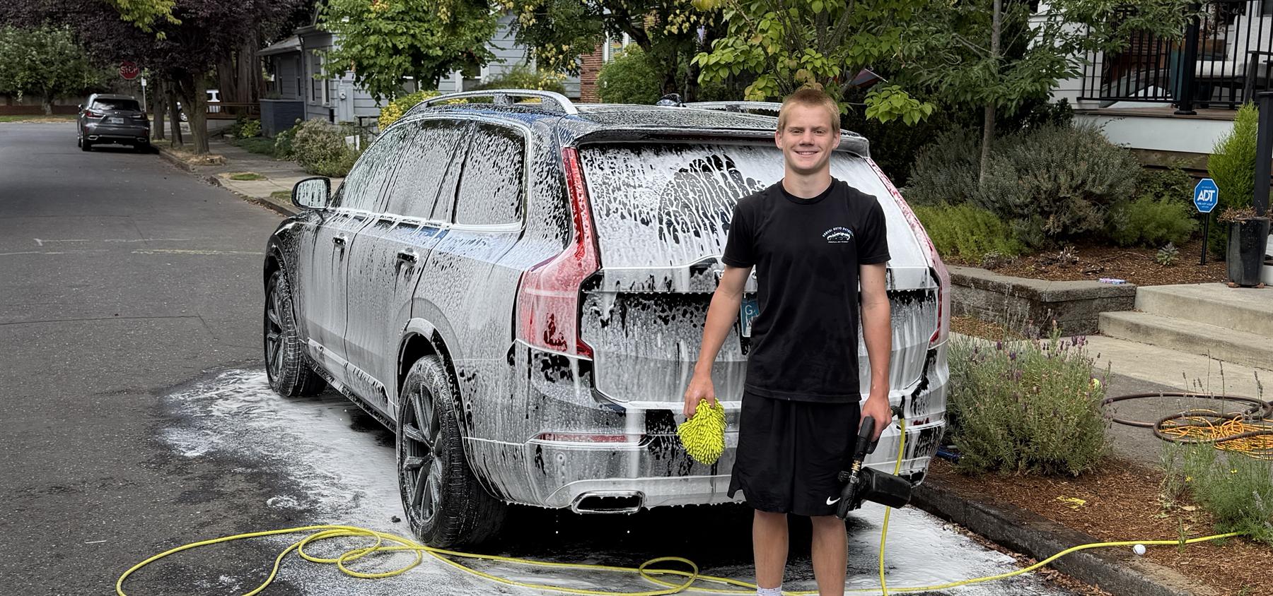 Bronx Carpenter, owner of Unreal Auto Detailing, beside a foam-covered SUV in Grant Park, NE Portland